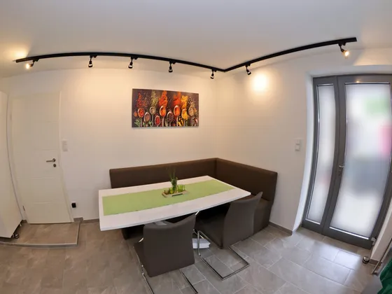 Dining area with a corner bench, table and a wall painting