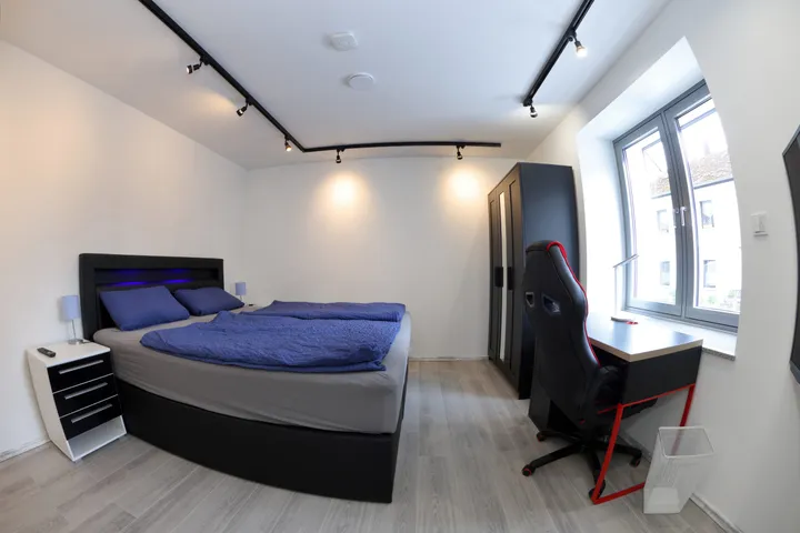 Bedroom with a box-spring bed, wardrobe and desk workspace