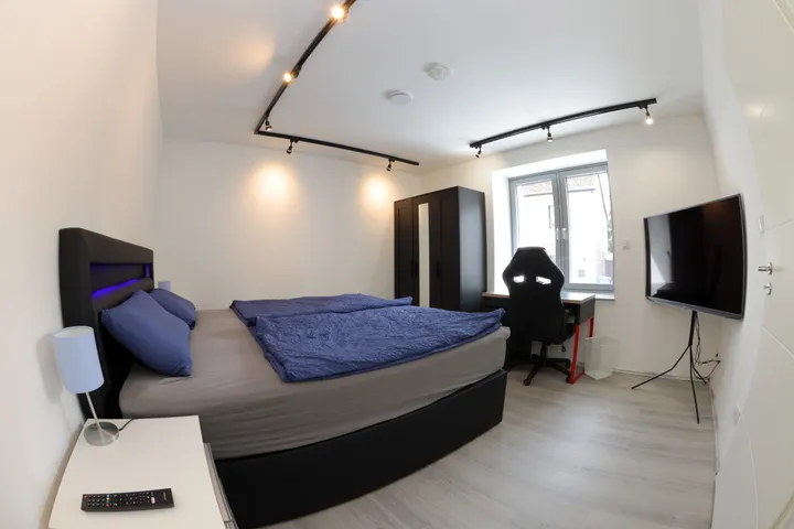 Bedroom with box-spring bed, smart TV and office chair