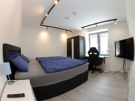 Bedroom with box-spring bed, smart TV and office chair